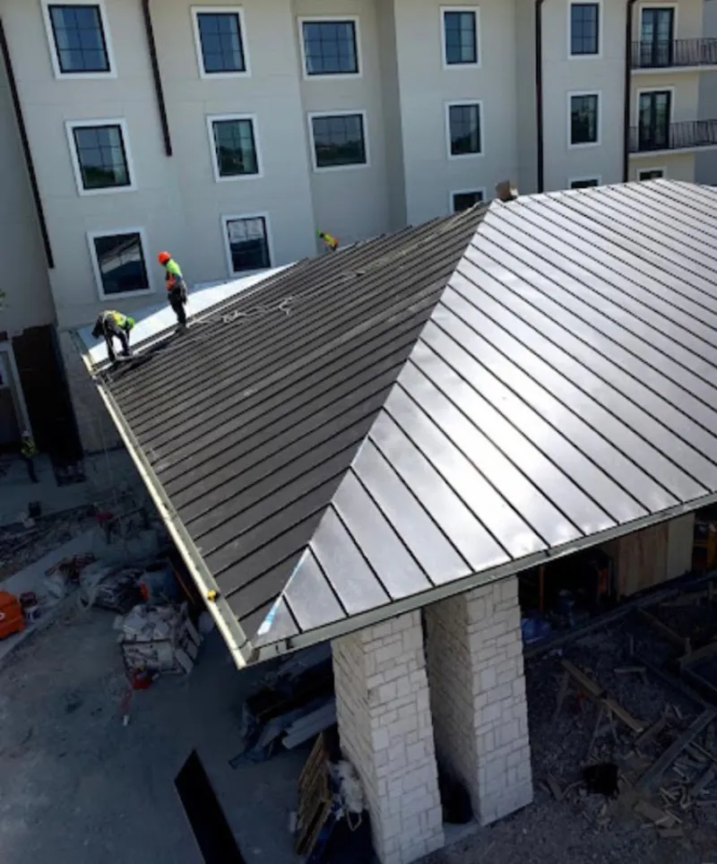 Crew installing standing seam metal roof panels on a commercial project in Winterset